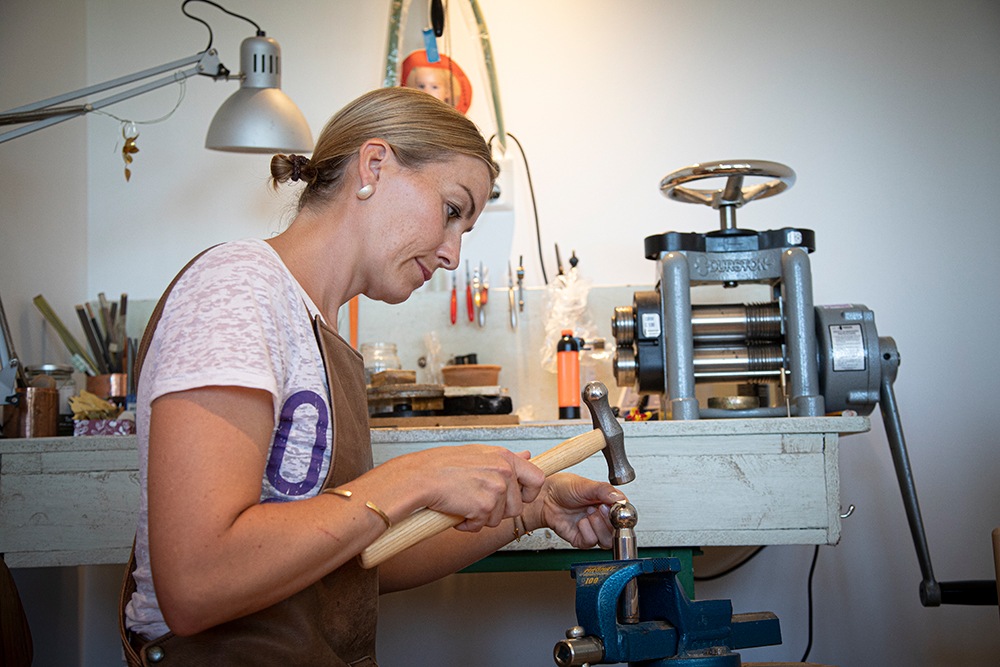 Hedvig Sommerfeldt har festet et knoppstempel til skrustikken som metallet formes etter, alt etter hammeren slår opp formen. (Foto: Mats Linder)